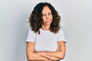 Orta yaşlı, kollarını kavuşturmuş, şüpheci ve sinirli İspanyol bir kadın sorun yüzünden surat asıyor. negatif kişi. 