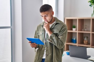 Genç İspanyol adam evde şüpheli bir ifadeyle dokunmatik ped kullanıyor.