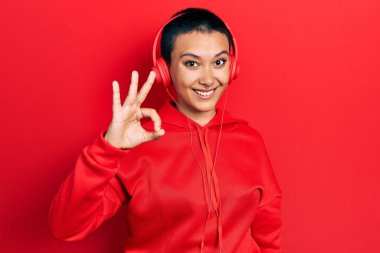 Kısa saçlı, müzik dinleyen, kulaklık takan, gülümseyen, el ve parmaklarıyla 