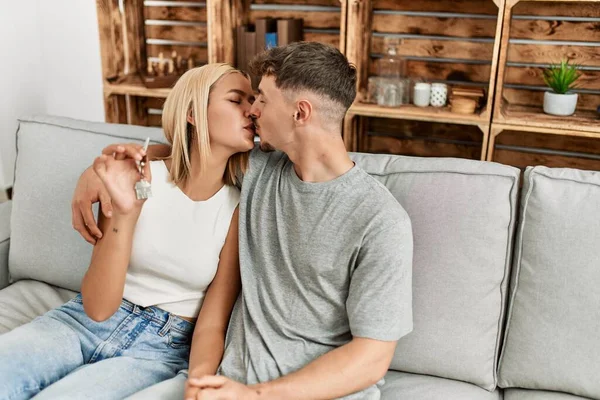 Young Caucasian Couple Kissing Holding Key New Home Sititng Sofa — Stockfoto