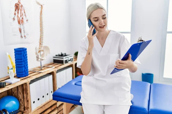 Young Caucasian Woman Wearing Physio Therapist Uniform Talking Smartphone Clinic — Fotografia de Stock