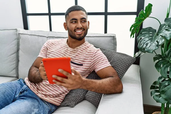 Young arab man smiling confident using touchpad at home