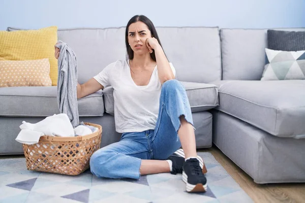 Genç esmer kadın evde çamaşırlarını yıkıyor ve kafası karışık. şüphe kavramı. 