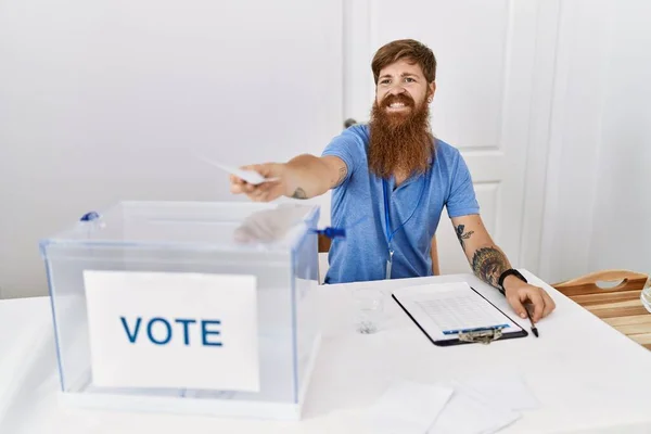 Young redhead politic party worker smiling happy holding vote at electoral college.