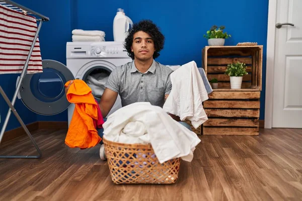 有卷发的西班牙裔男子在洗衣房洗衣服 脸上带着严肃的表情 简单而自然地看着相机 — 图库照片