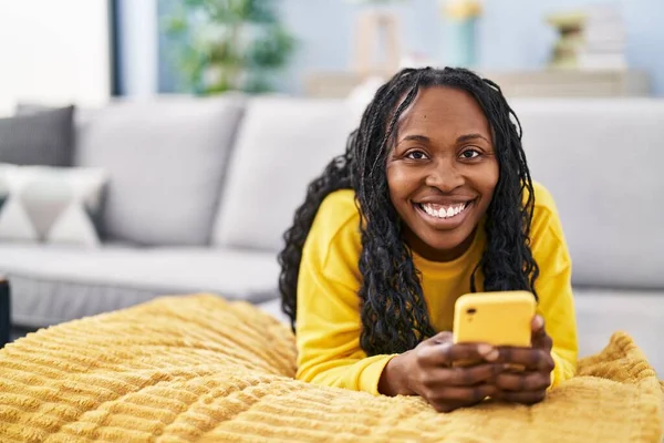 Afroamerykanka Pomocą Smartfona Leżącego Kanapie Domu — Zdjęcie stockowe