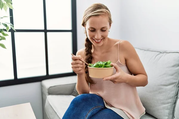 Young caucasian woman smiling confident eating salad at home