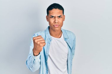 Genç, Afro-Amerikalı, günlük kıyafetler giymiş kızgın ve kızgın. Öfkeyle bağırırken yumruk kaldırıyor. öfke ve agresif konsept. 