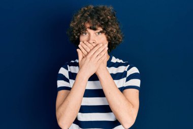 Sıradan çizgili tişört giyen yakışıklı genç adam yanlışlıkla ağzı ellerle kapatmış. gizli kavram. 