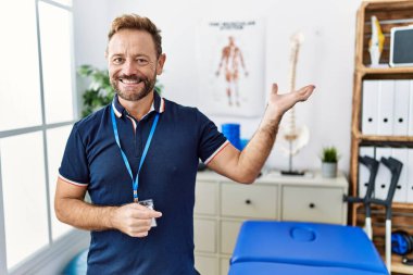 Orta yaşlı fizyoterapist. Ağrı giderme kliniğinde çalışıyor. Gülümsüyor.. 