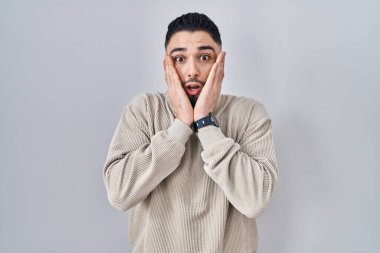 Soyutlanmış arka planda duran genç yakışıklı adam korkmuş ve şok olmuş, şaşırmış ve şaşırmış bir yüz ifadesi var. 