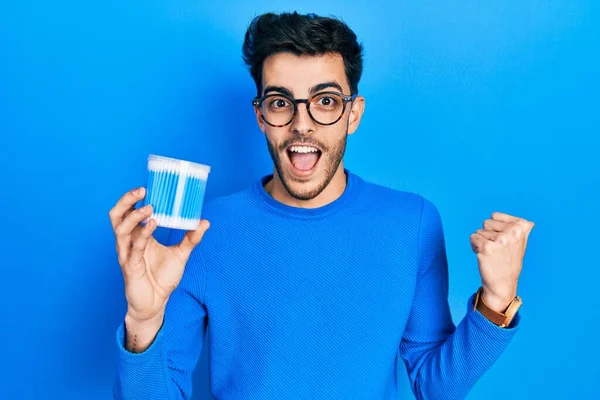 Young Hispanic Man Holding Earwax Cotton Remover Pointing Thumb Side — Stock Photo, Image