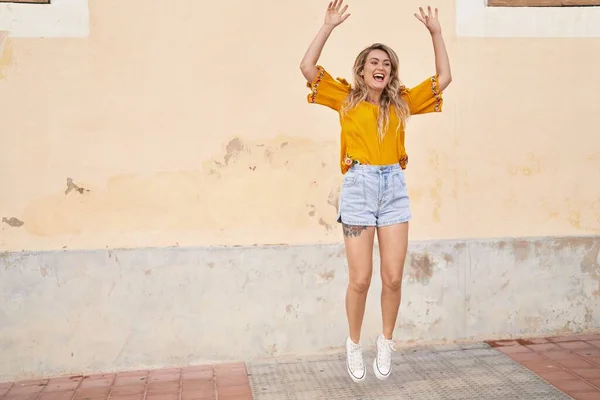 Young woman smiling confident jumping at street