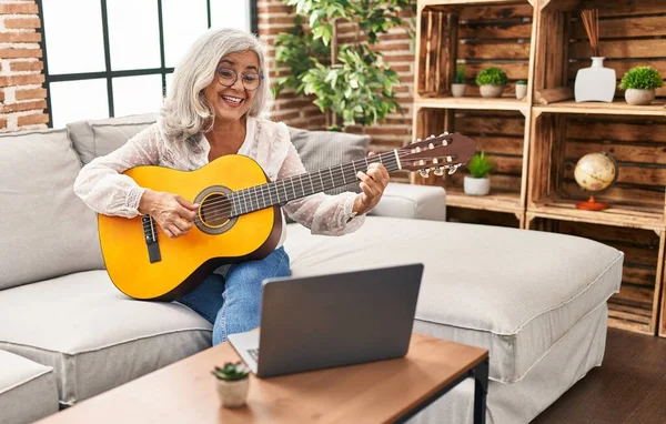 Orta yaşlı bir kadının evde online gitar dersi var.
