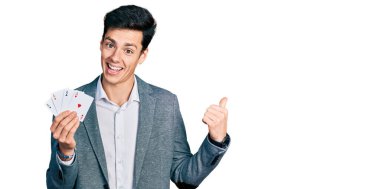 Poker oynayan genç İspanyol iş adamı başparmağını kaldırarak ağzını açarak gülümsüyor. 