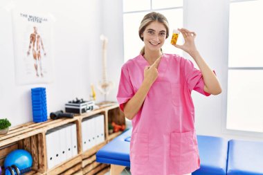 Ağrı kesici kliniğinde çalışan genç fizyoterapist kadın elinde haplarla mutlu mesut elini ve parmağını gösterdi. 