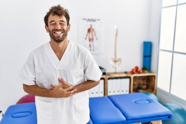 Genç, yakışıklı fizyoterapist. Ağrı giderme kliniğinde çalışıyor. Gülümsüyor ve kahkahalar atıyor.. 