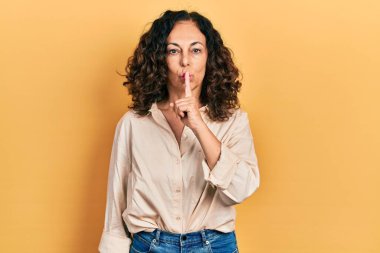 Orta yaşlı İspanyol kadın gündelik kıyafetler giyip parmakları dudaklarında sessiz olmak istiyor. sessizlik ve gizli konsept. 