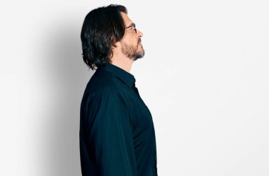 Orta yaşlı, günlük kıyafetler ve gözlük takan, rahat bir görünüm takınan, kendine güvenen bir gülümsemesi olan beyaz bir adam.. 