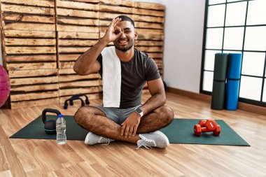 Spor salonundaki antrenman minderinde oturan genç Hintli adam el hareketleriyle gülümsüyor ve mutlu yüzüyle parmaklarının arasından bakıyor.. 
