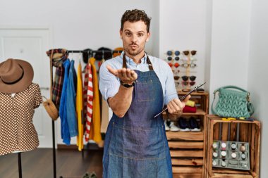 Perakende mağazasında yönetici olarak çalışan yakışıklı genç bir adam kameraya bakıp havada öpücükler savuruyor. Güzel ve seksi. aşk ifadesi. 