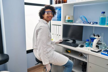 Laboratuvarda bilgisayar kullanan İspanyol bir bilim adamı üniforması giyiyor.