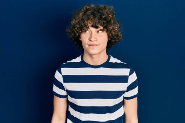 Yakışıklı genç adam, sıradan çizgili tişört giyiyor. Gülümsüyor, yan tarafa bakıyor ve düşünüyor.. 