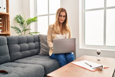 Psikoloji merkezinde dizüstü bilgisayar kullanan genç sarışın kadın psikolog.