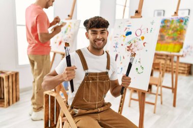 Resim stüdyosunda kendine güvenen iki İspanyol erkek gülümsüyor.