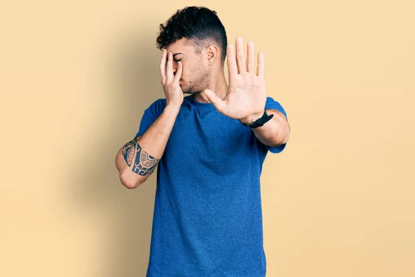 Молодий Іспаномовний Чоловік Носить Повсякденну Футболку Прикриваючи Очі Руками Роблячи — стокове фото