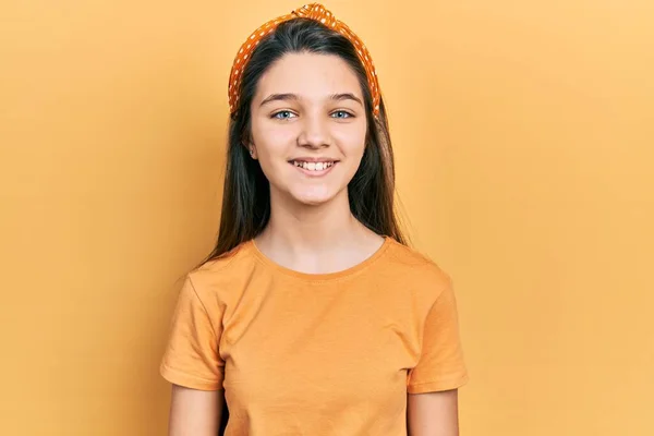 年轻的黑发女孩穿着休闲的橙色T恤 站在那里 面带微笑 露出自信的笑容 露出牙齿 — 图库照片