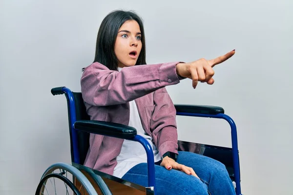 Young Brunette Woman Sitting Wheelchair Pointing Finger Surprised Ahead Open — Foto Stock