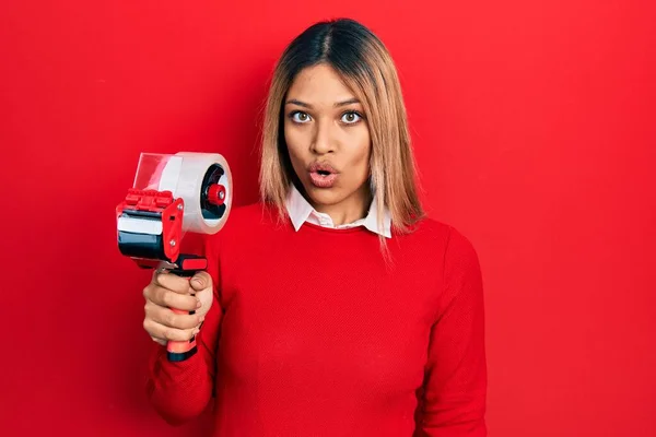 Beautiful Hispanic Woman Holding Packing Tape Scared Amazed Open Mouth — Stock Photo, Image