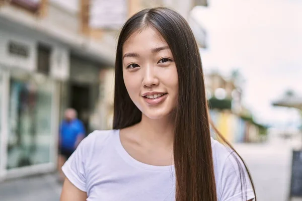 Young chinese girl smiling happy standing at the city.