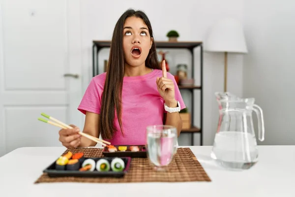 若いですブルネット女性食べる寿司箸驚きと驚きを見て上と指で指し 腕を上げ — ストック写真