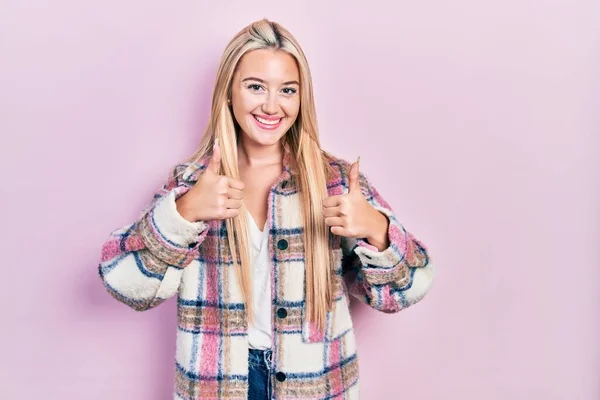 Young blonde girl wearing casual clothes success sign doing positive gesture with hand, thumbs up smiling and happy. cheerful expression and winner gesture.
