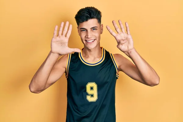 Молодой Латиноамериканец Баскетбольной Форме Показывает Пальцем Номер Девять Улыбаясь Уверенно — стоковое фото