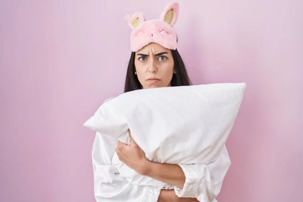 Young Brunette Woman Wearing Sleep Mask Pajama Hugging Pillow Skeptic —  Fotos de Stock