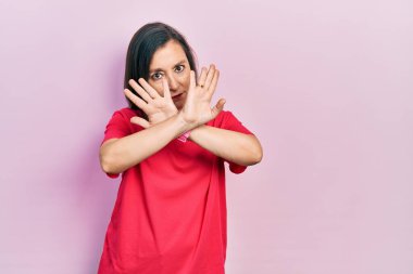 Orta yaşlı İspanyol kadın gündelik kıyafetler giyiyor. Reddedilmiş yüz ifadesi. Kollarını kavuşturuyor. 