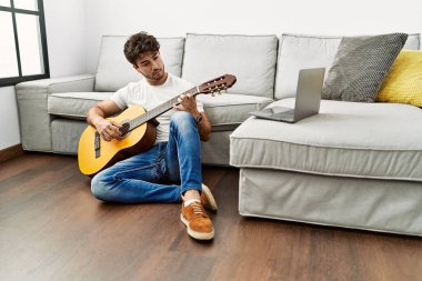 Genç İspanyol adam evde klasik gitar çalıyor.