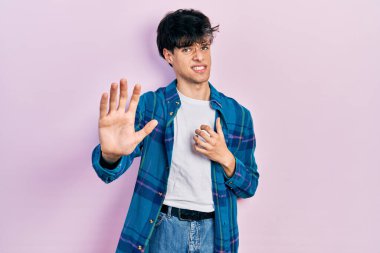 Yakışıklı hippi genç adam gündelik beyaz tişört ve antika gömlek giyiyor. İftira reaksiyonu yüzünden tiksinti ve tiksinti ifadesi takınıyor. Eller havada. 