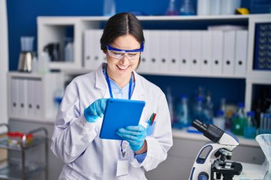 Young woman scientist using touchpad at laboratory