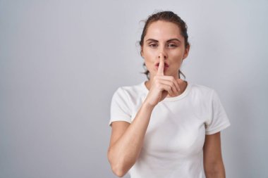 Güzel esmer kadın izole edilmiş arka planda duruyor ve parmakları dudaklarında sessiz olmak istiyor. sessizlik ve gizli konsept. 