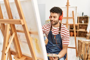 Sanat stüdyosunda müzik dinleyen genç bir Arap sanatçı..