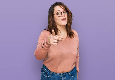 Genç, cüsseli, sıradan kıyafetler giyen ve gözlüklü bir kadın kameraya kızgın ve sinirli olduğunu gösteriyor. 