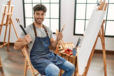 Genç İspanyol sanatçı gülümsüyor. Resim stüdyosunda fırça tutarken mutlu..
