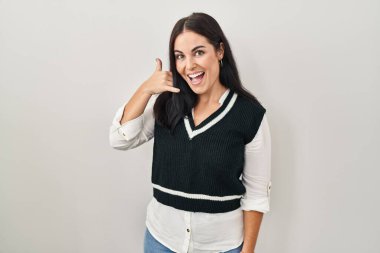 Soyutlanmış arka planda duran genç İspanyol kadın telefonla el ve parmak hareketleriyle gülümsüyor, telefonda konuşuyor gibi. iletişim kavramları. 