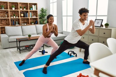 Genç Latin sporcu çift gülümseyerek evde mutlu bir antrenman yapıyor..