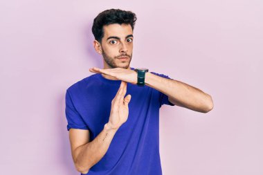 Gündelik tişört giyen genç İspanyol adam. Elleriyle jest yapıyor, hayal kırıklığına uğramış ve ciddi bir yüz ifadesi takınıyor. 