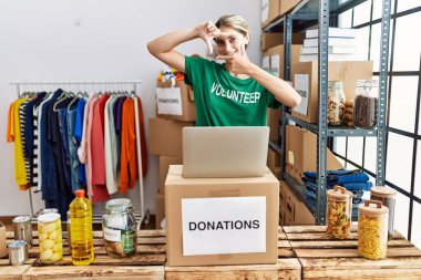 Bağışta gönüllü tişört giyen genç sarışın kadın gülümsüyor ve mutlu yüzlü eller ve parmaklarla çerçeve yapıyor. yaratıcılık ve fotoğrafçılık kavramı. 